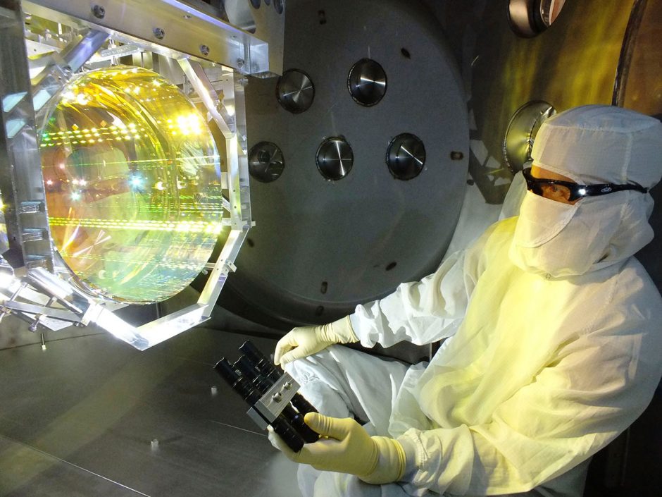 scientist wearing mask and goggles works with bright device