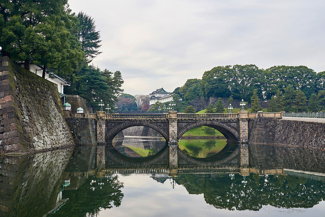 bridge over still water with Japanese-style buildings in distance