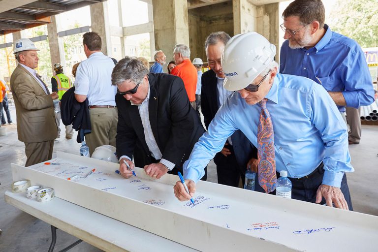 a group of men signing the beam