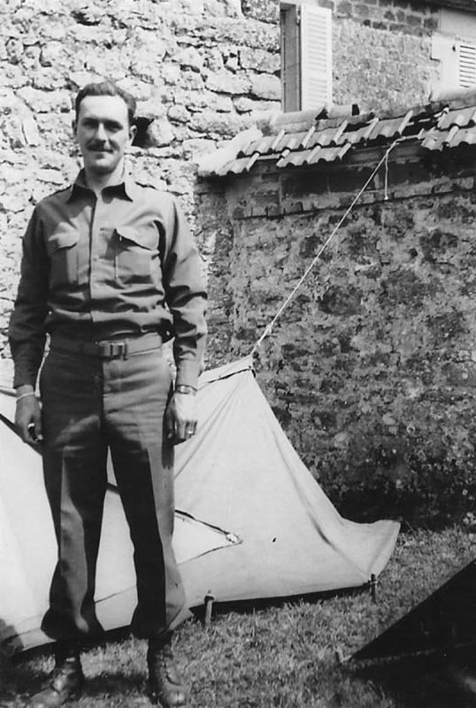 photo of Frank Towers standing in front of tarpaulin and stone wall