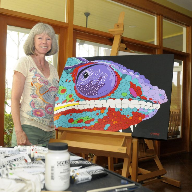 Cindy standing with painting of chameleon