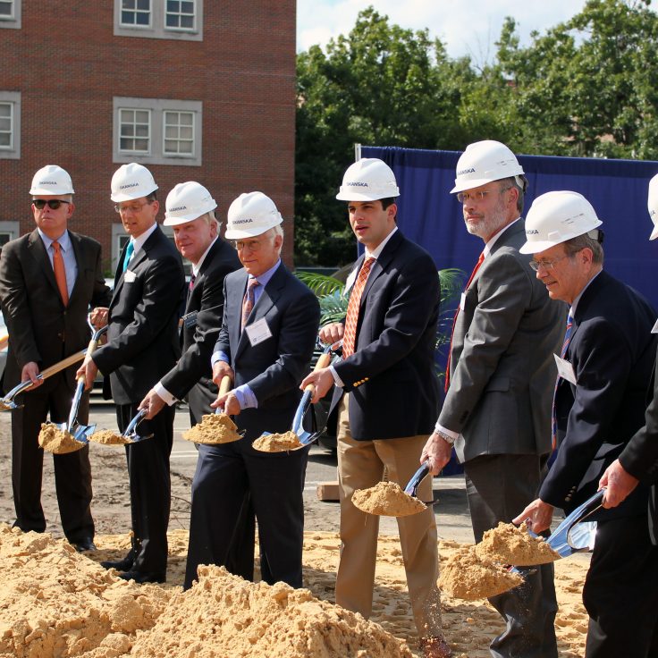 A group of men hold shovels at the ceremonial groundbreaking