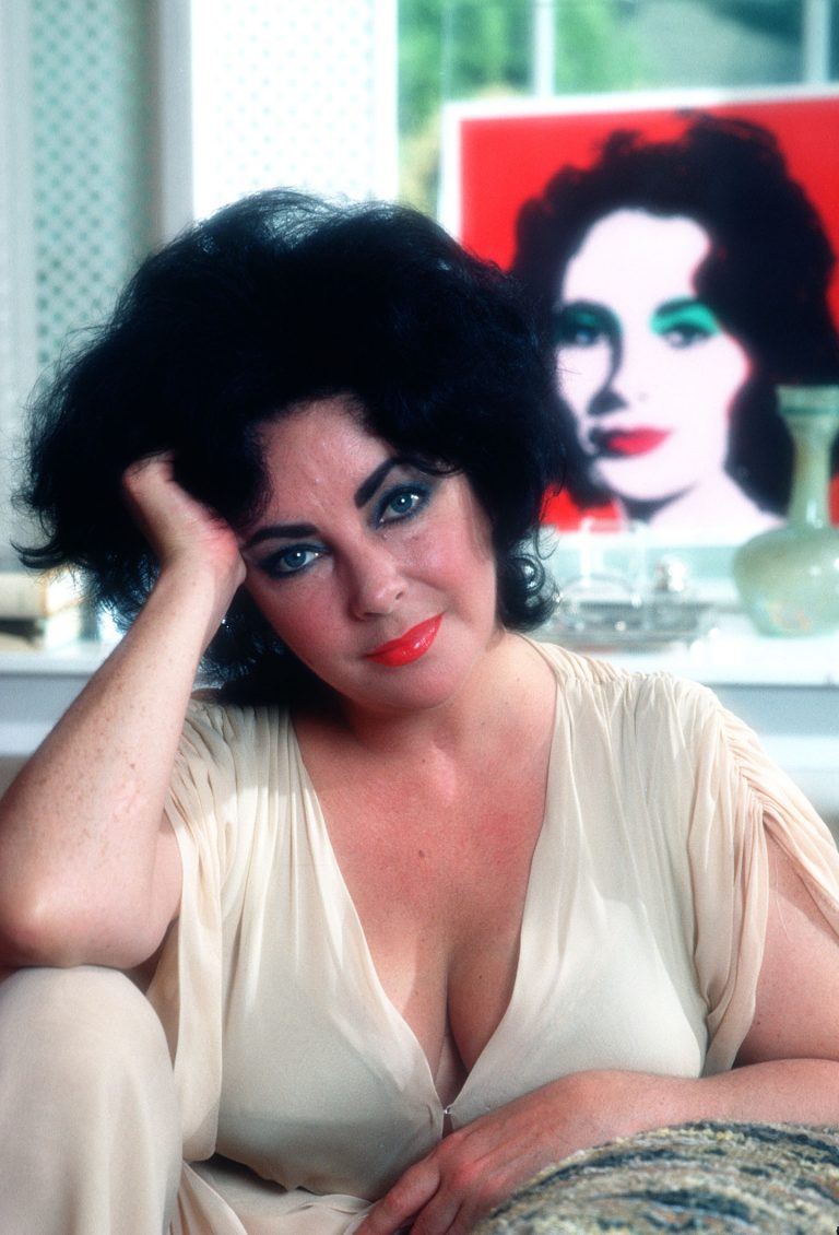 portrait of Elizabeth Taylor lounging in front of Andy Warhol painting of her likeness