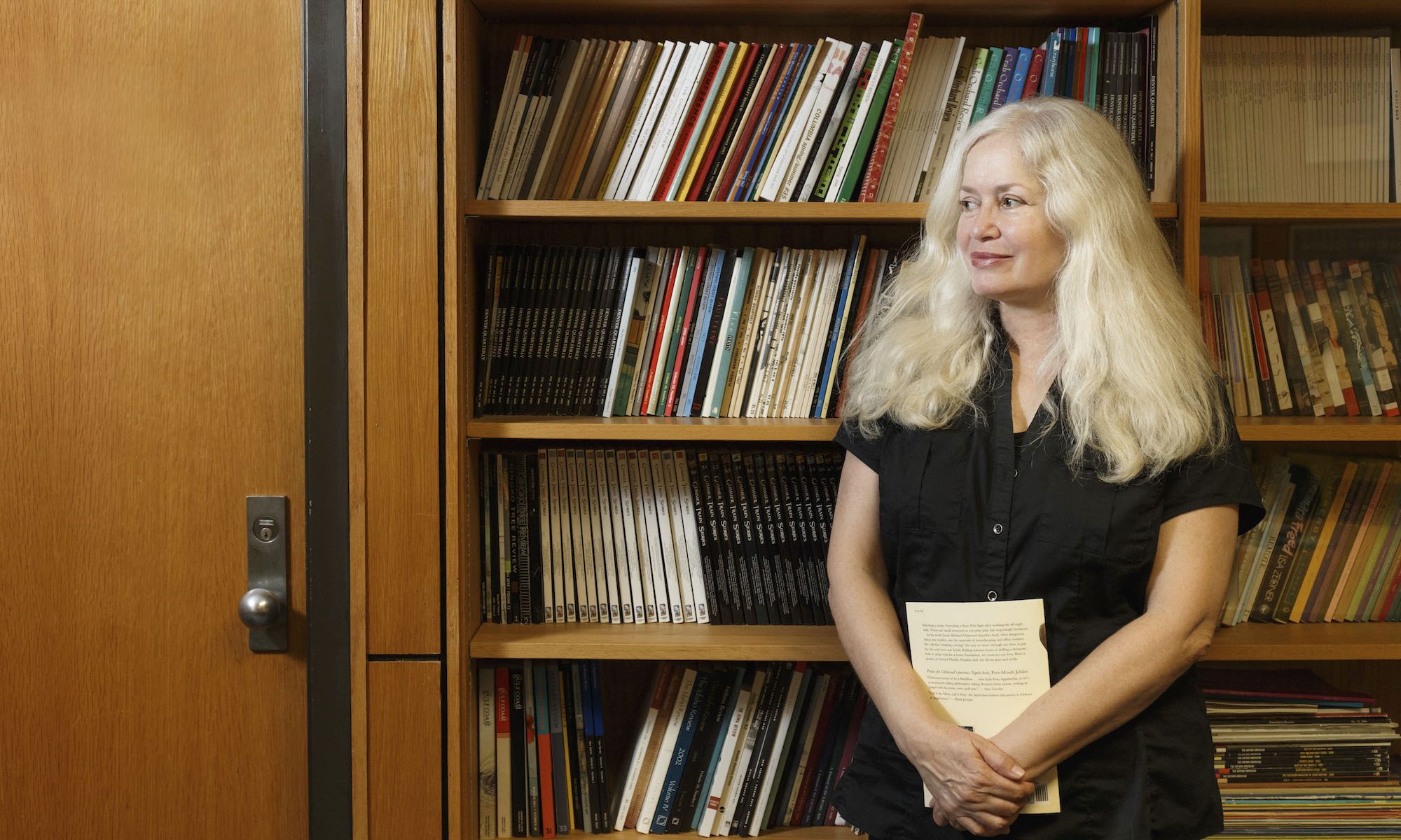 Amy Hempel stands in front of bookcase