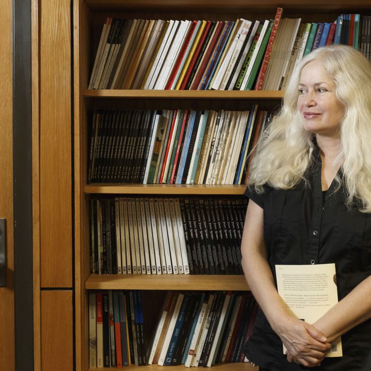 Amy Hempel stands in front of bookcase