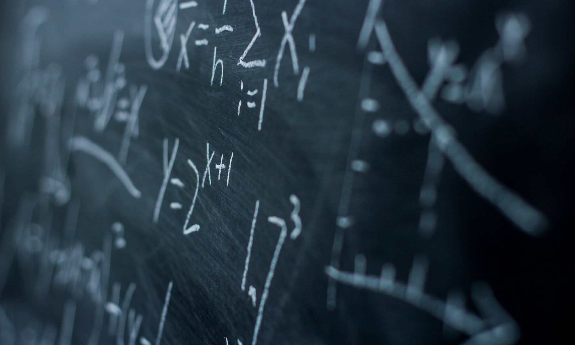 Math formulas written by white chalk on a blackboard.