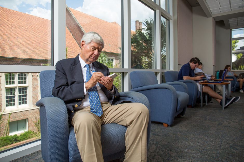 grandfatherly man sits in comfy chair and interacts with mobile device