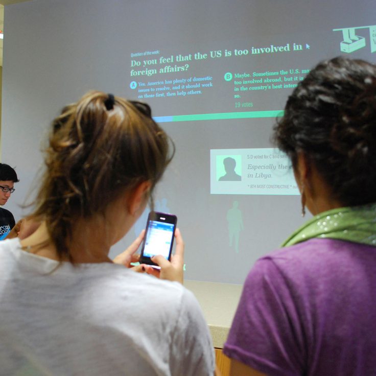 students use devices to engage with survey displayed on large screen in front of them