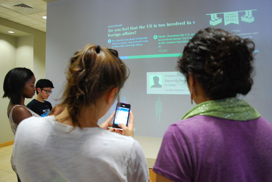 students use devices to engage with survey displayed on large screen in front of them