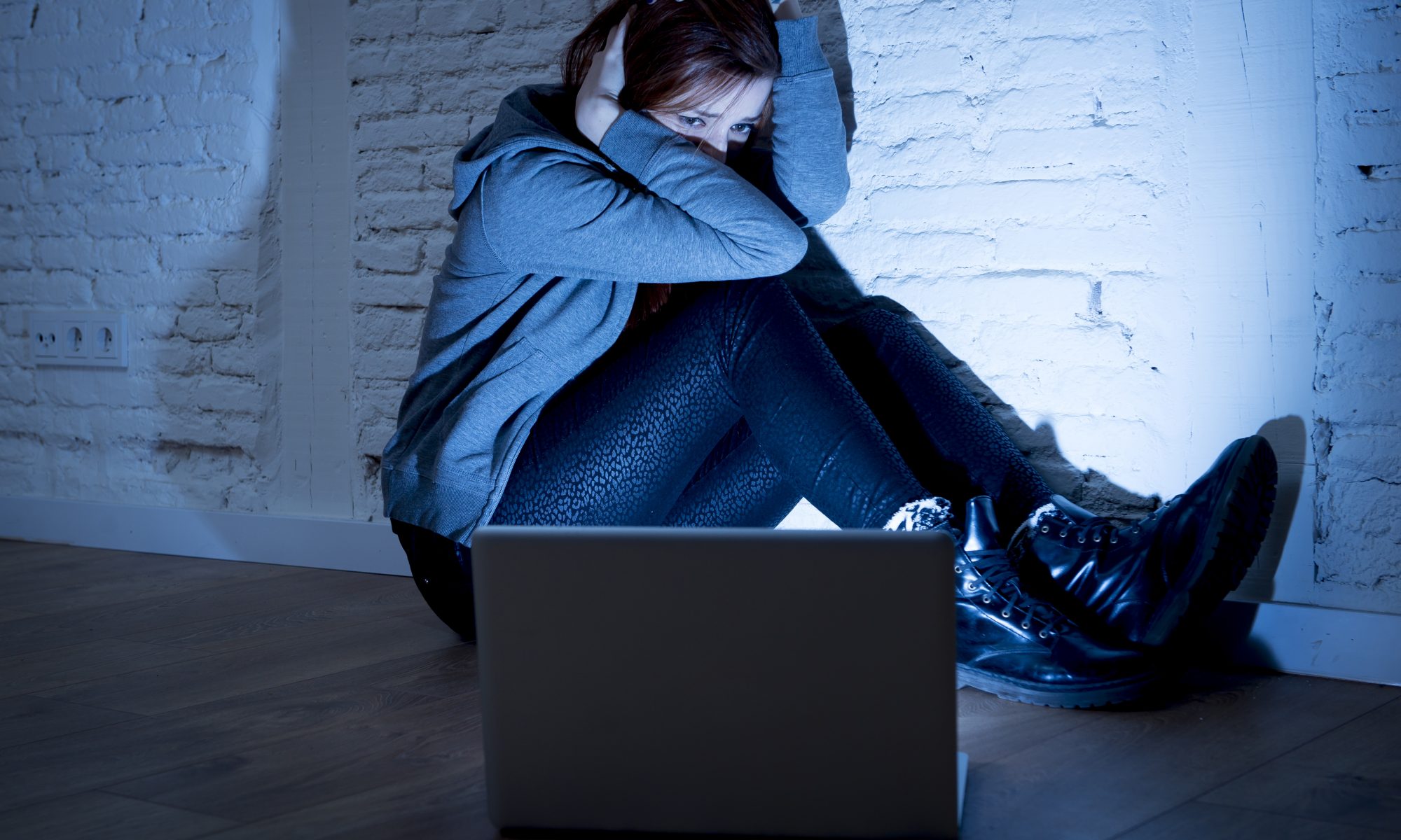 sad and scared female teenager with computer laptop suffering cyberbullying and harassment being online abused by stalker or gossip feeling desperate and humiliated in cyber bullying concept