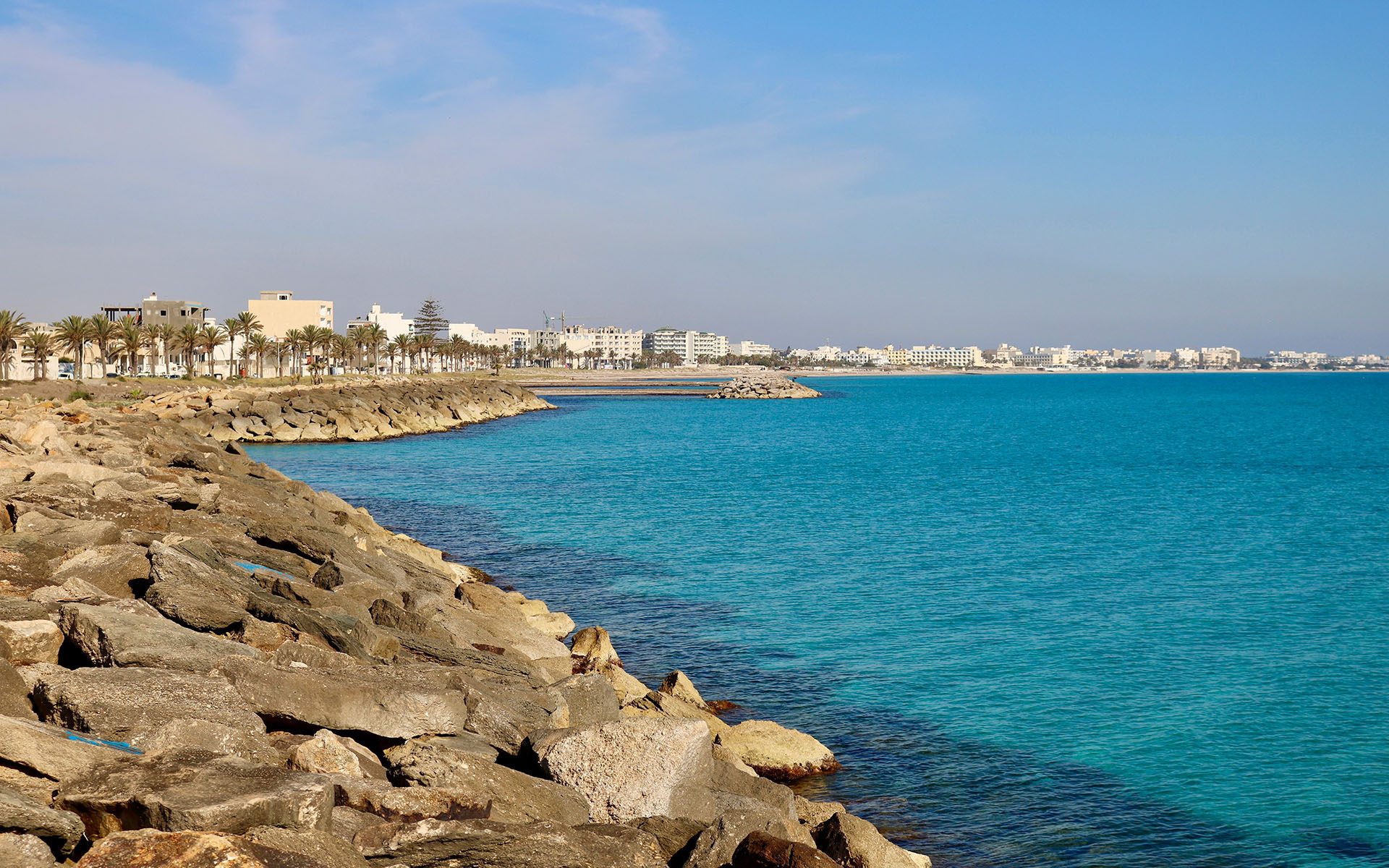 rocky shoreline with stunning blue waters, with cityline in background
