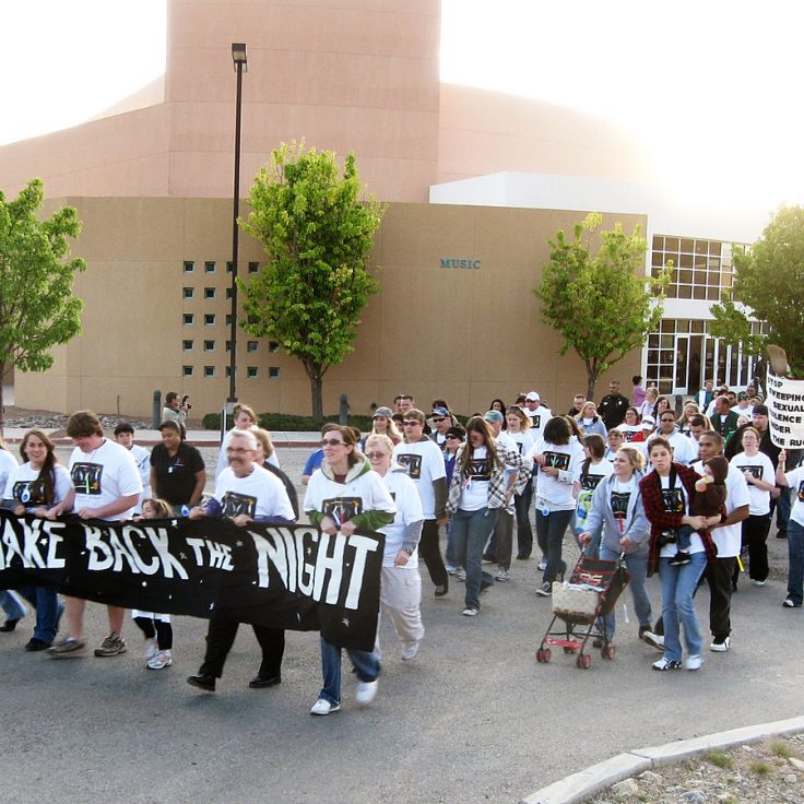 photo of women marching holding signs that read Take Back the Night
