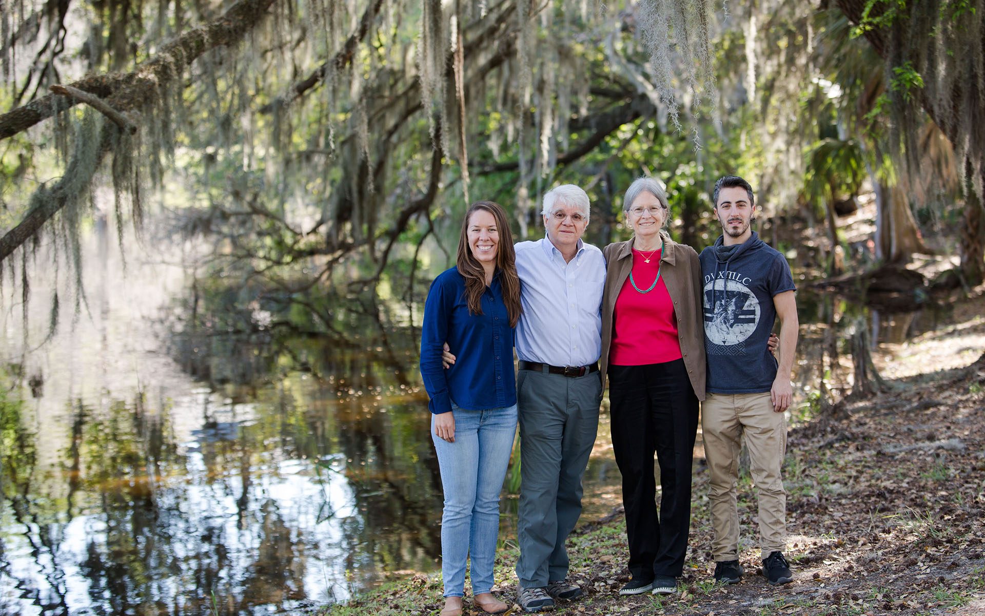 group of four people standing under Spanish moss-drenched trees by idyllic lake