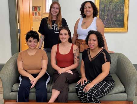 First year graduate students gather in the Center for a group photo. Pictured are (left to right standing) Kelsey Malles, Ebonee Brown, (left to right seated) Nagdeska Paulino, Beth Holden, and Elisa Rios.