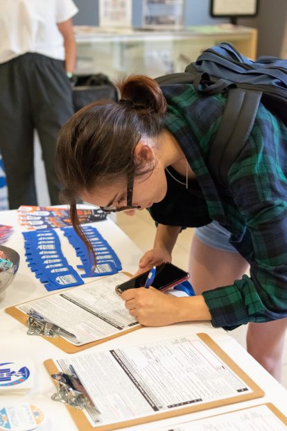 A student completes voter registration forms at a campus event. 