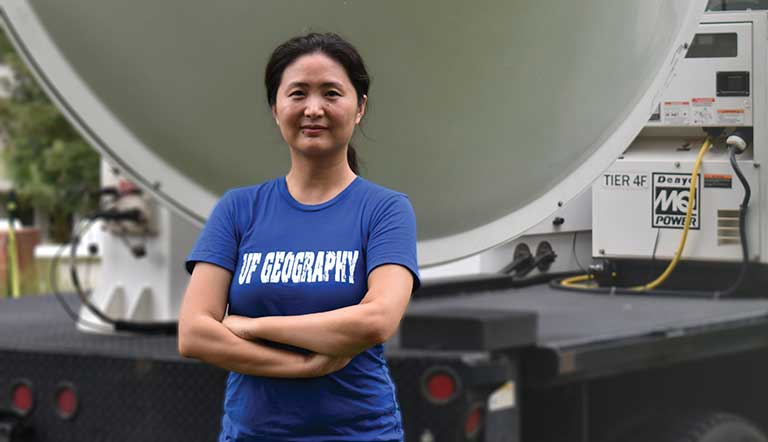 Researcher stands with arms folded in front of mobile radar unit equipment.