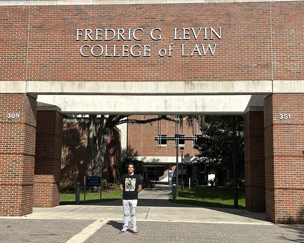 photo of Kevin Guirola standing in front of a façade that displays the words, Fredric G Levin College of Law