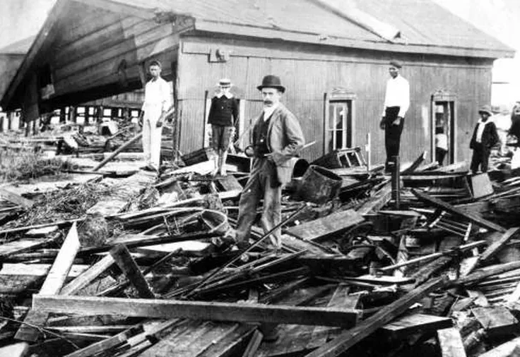 A black and white photo of men standing amidst the wreckage of a building.