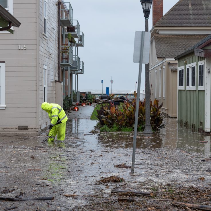 workers clean up a flooded road in a residential area