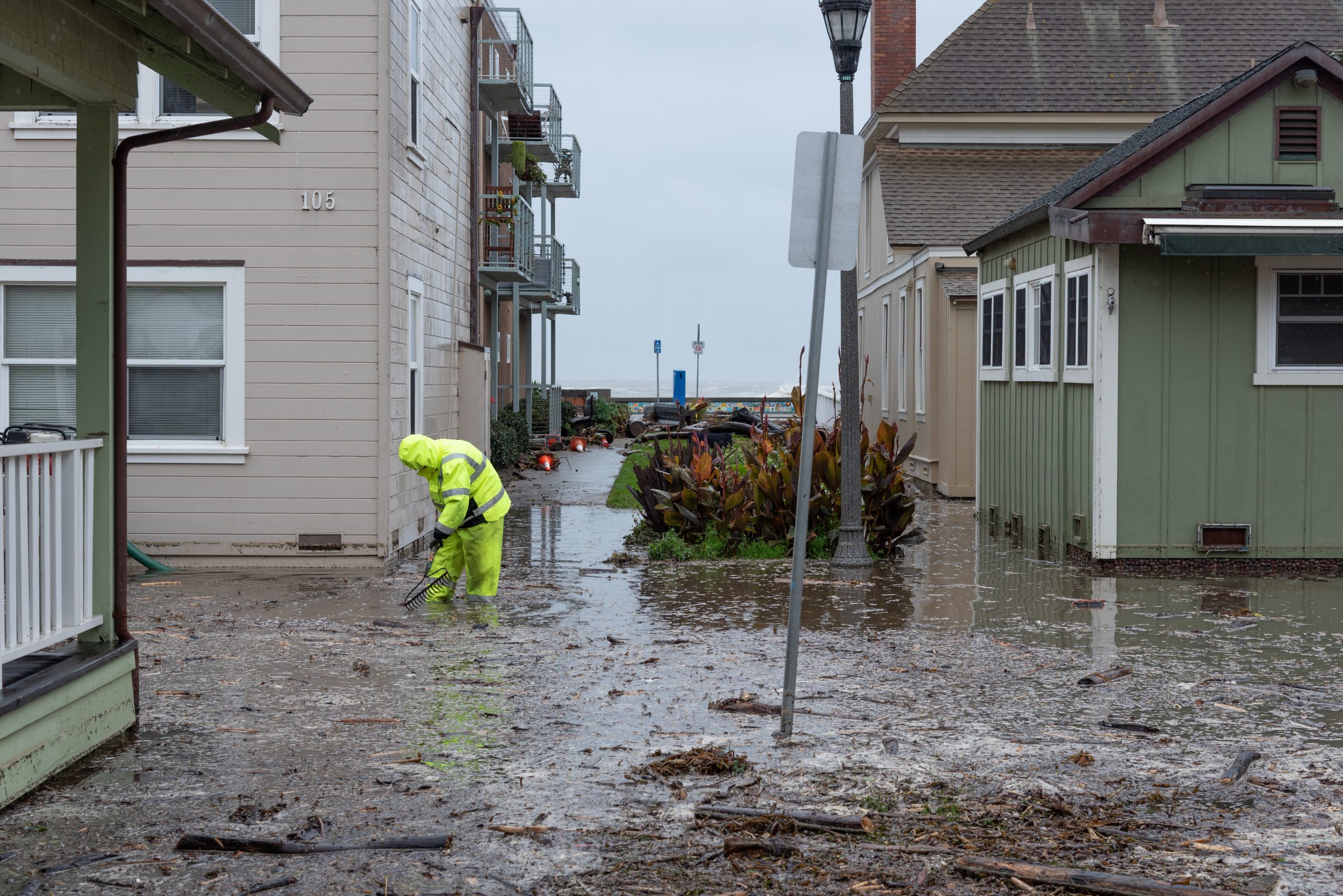 workers clean up a flooded road in a residential area