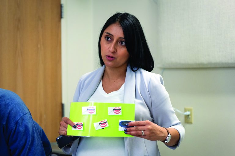 a professional woman holds up a card with mouths on it to demonstrate. 