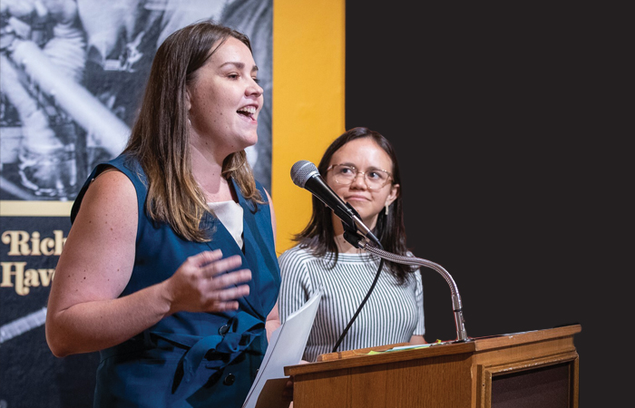 two women speak at a podium at an event