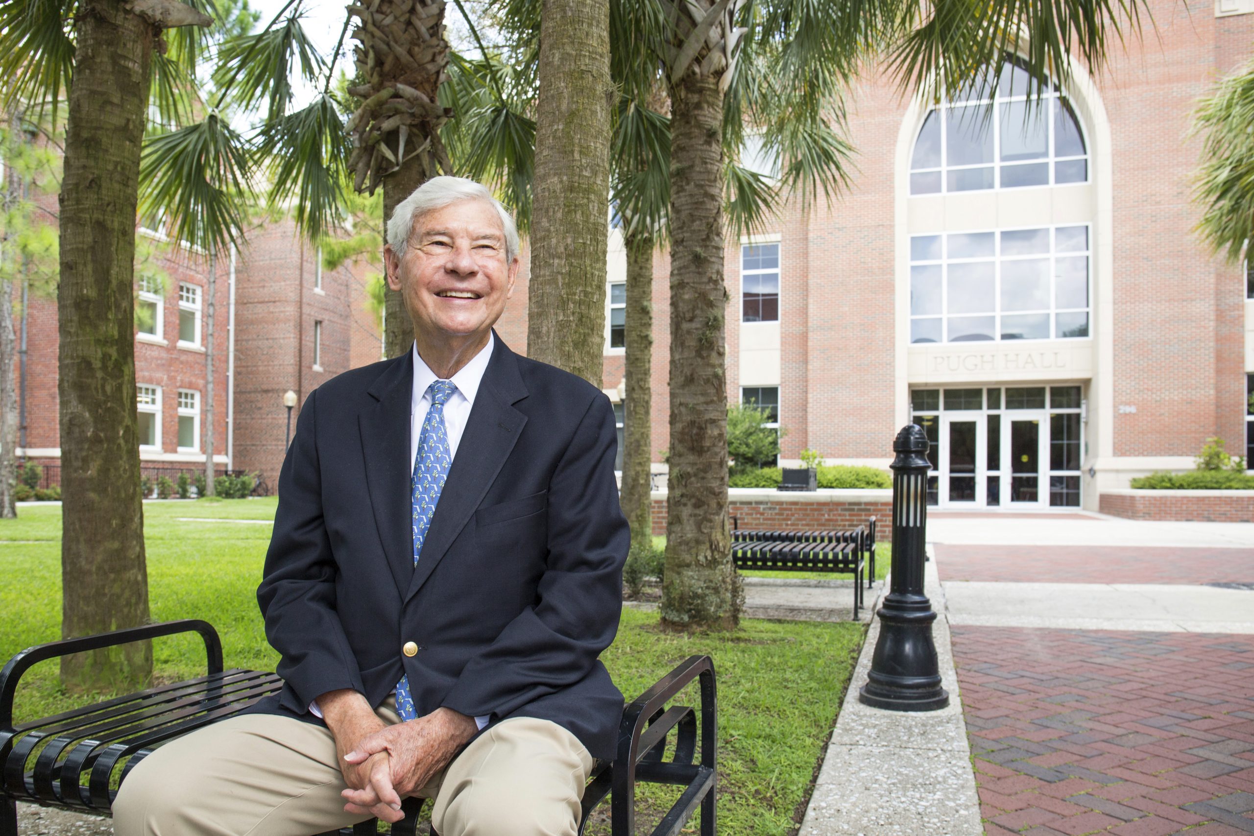 Bob Graham sits on a bench in front of a campus building