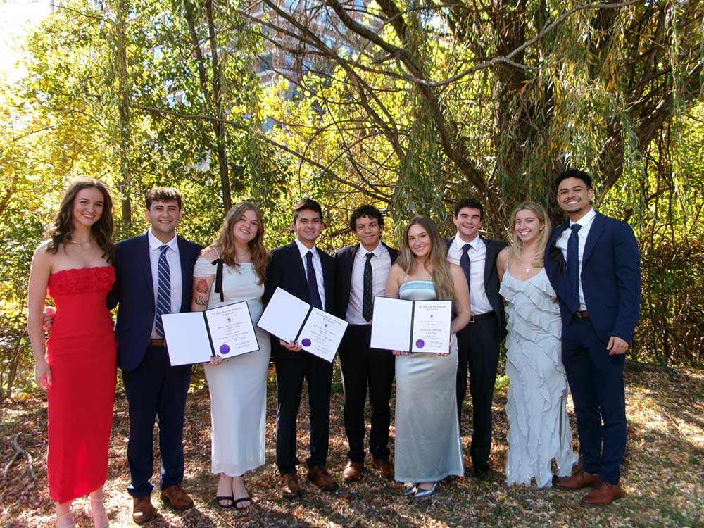 Row of nicely dressed students holding certificates