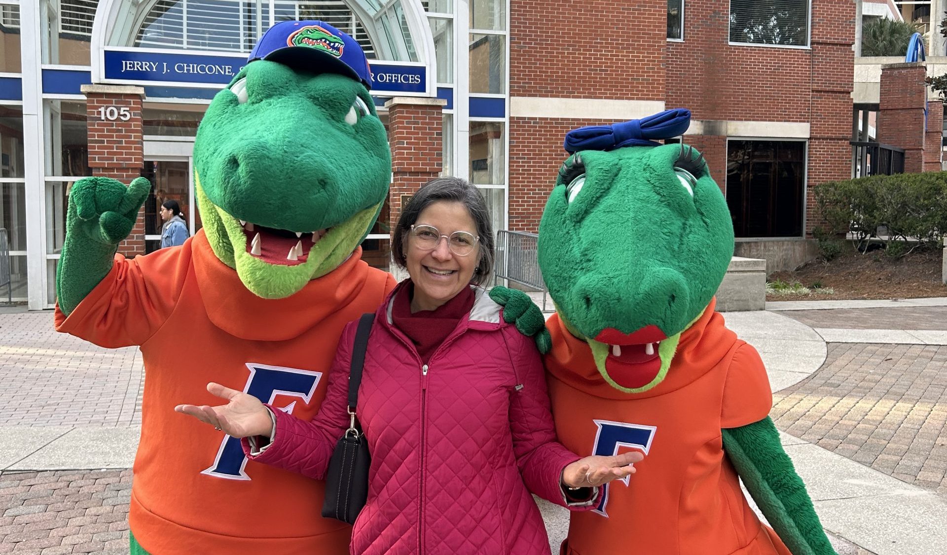 Woman standing between Gator mascots.